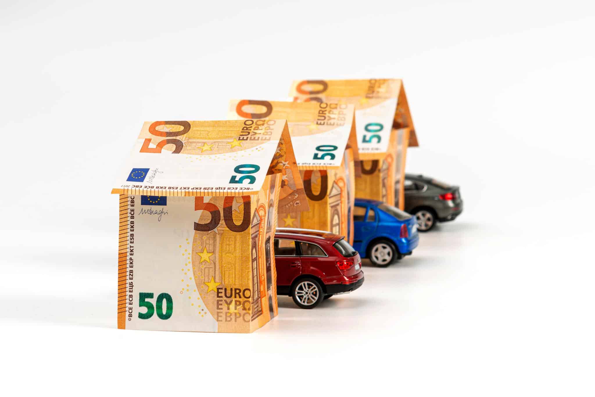 Houses from euro banknotes and cars isolated on white. loan, real estate and car insurance concept